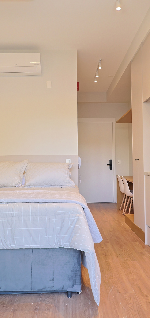 Obra pronta: Studio com cama de casal, armários claros, cozinha linear com nichos de madeira e piso amadeirado