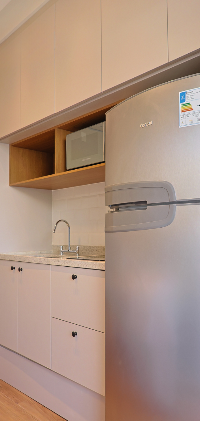 Obra pronta: Cozinha com armários claros, nicho de madeira com micro-ondas, geladeira inox e bancada de granito