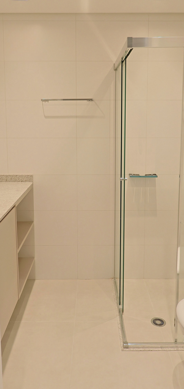 Obra pronta: Banheiro claro com box de vidro, bancada com nichos e vaso sanitário