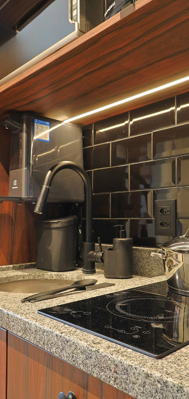 Obra pronta: Bancada de granito com cuba, cooktop de indução, torneira preta e revestimento preto com luz embutida