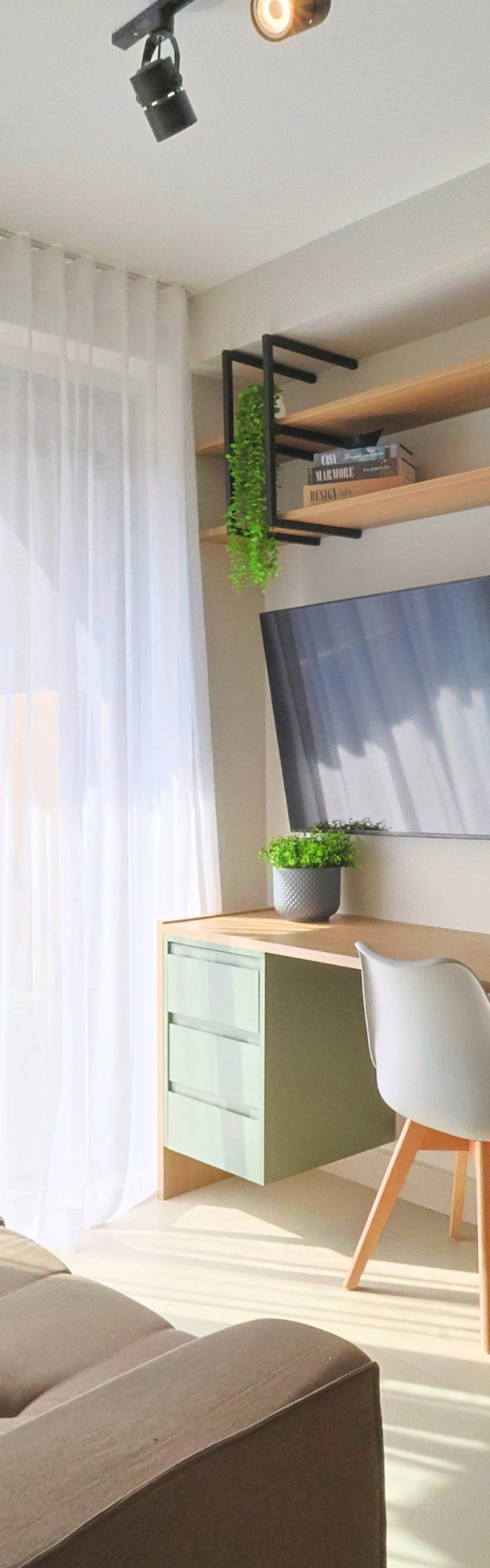 Obra pronta: Sala com sofá, mesa de trabalho verde e madeira, TV na parede e prateleiras com estrutura preta