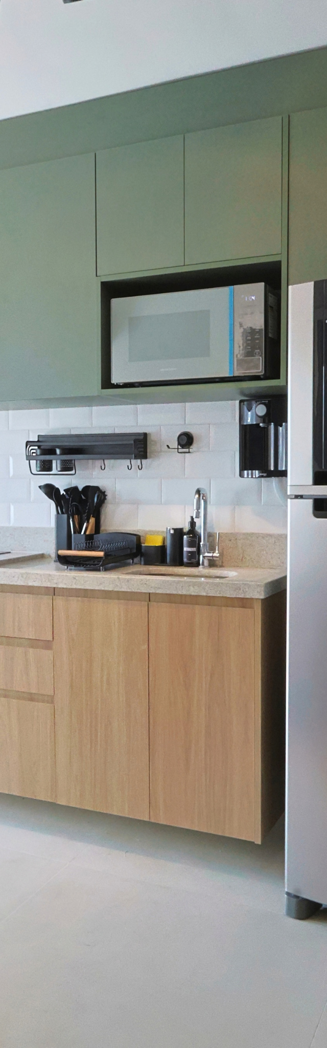 Obra pronta: Cozinha com armários verdes e de madeira, micro-ondas em nicho e geladeira inox