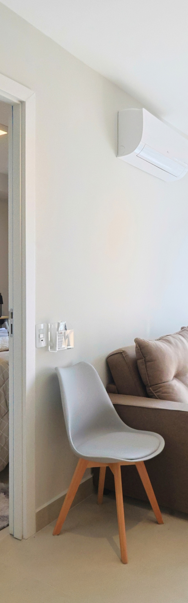 Obra pronta: Sala com sofá e cadeira cinza, ar-condicionado e porta aberta para o quarto