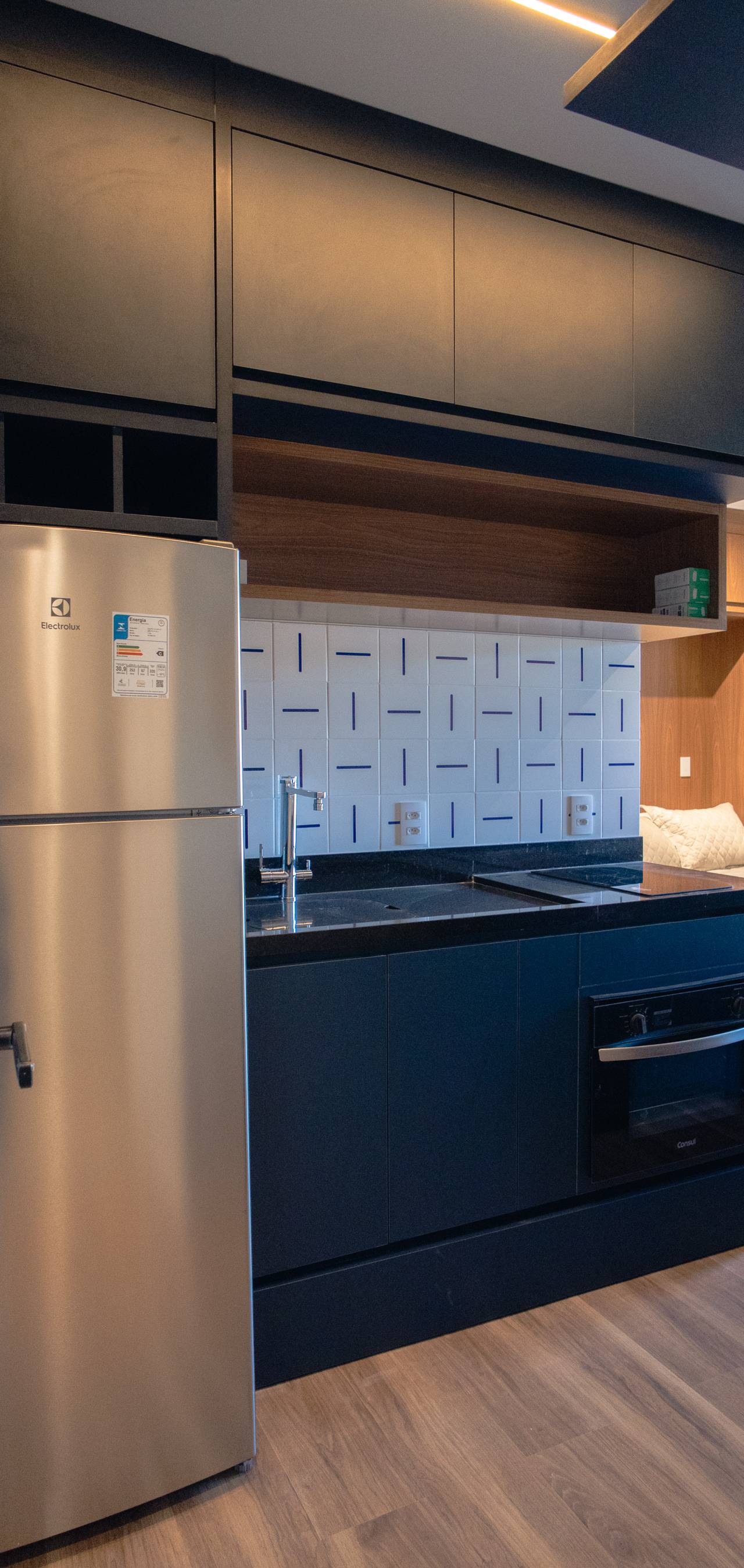 Obra pronta: Cozinha com armários azul-escuros, geladeira inox, forno embutido e revestimento branco com traços azuis