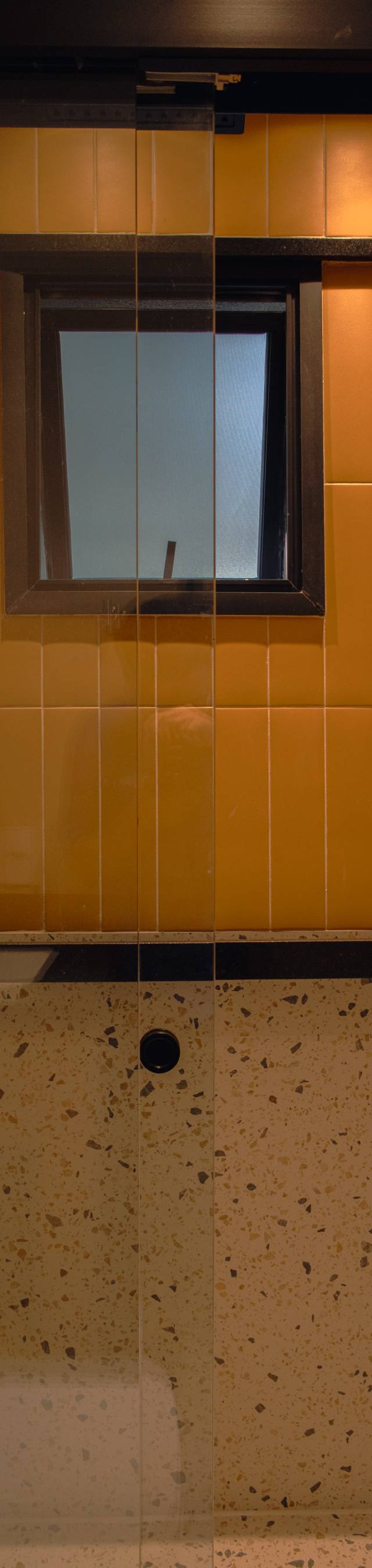 Obra pronta: Área do box com revestimento laranja até meia altura, granilite abaixo e chuveiro com ducha