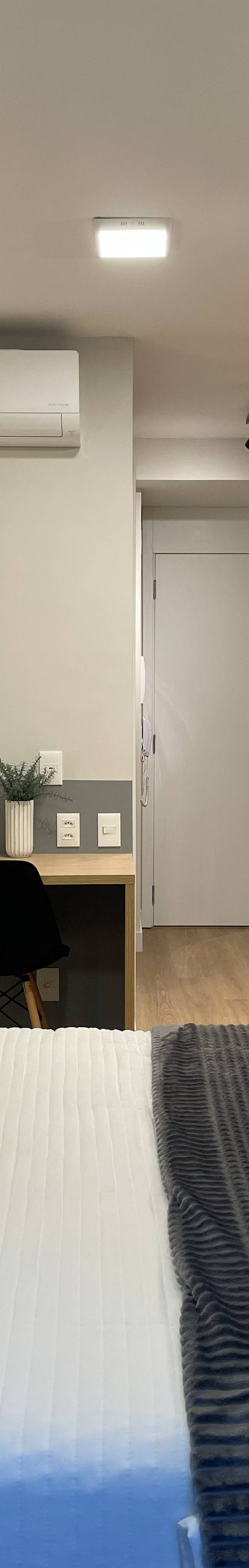 Obra pronta: Studio visto da cama: bancada de trabalho com cadeiras pretas, cozinha e porta de entrada