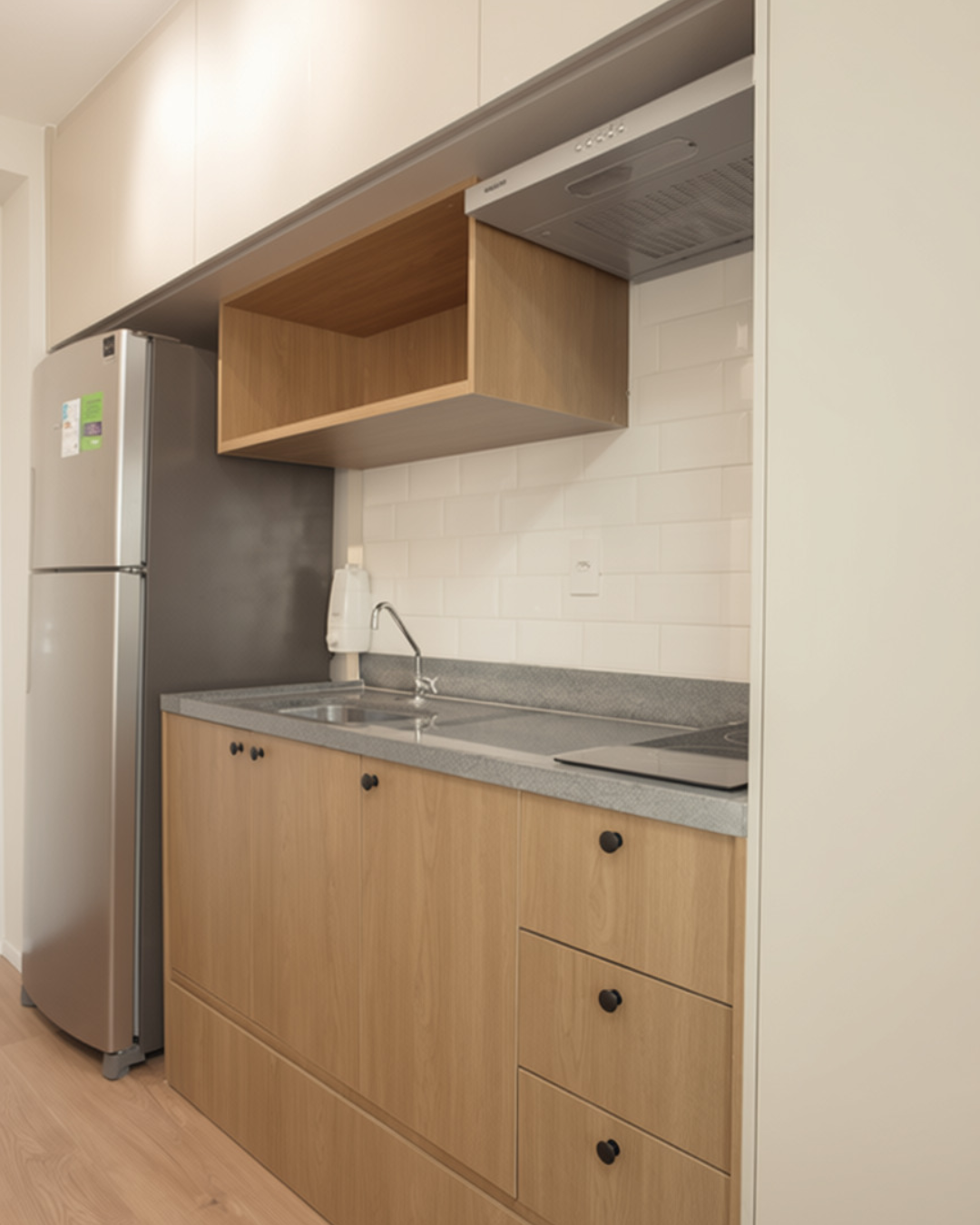 Obra pronta: Cozinha com gabinete de madeira, bancada cinza, cooktop, coifa e nicho de madeira