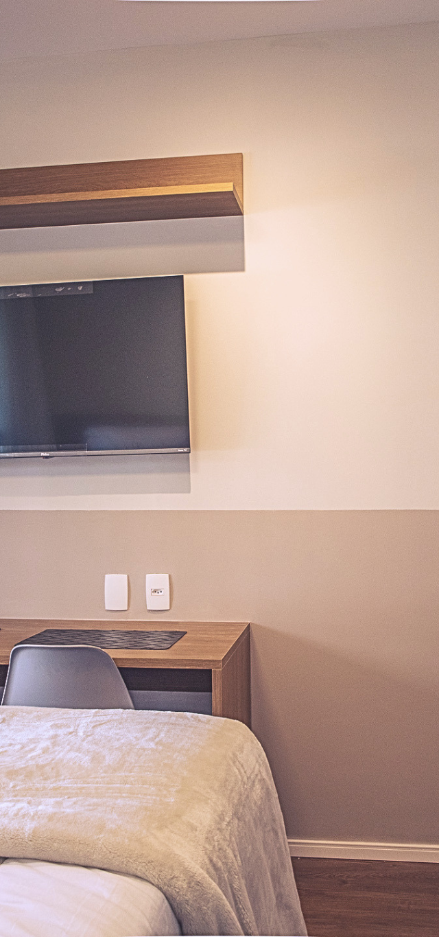 Obra pronta: Studio com cama de casal, TV na parede, mesa de madeira com duas cadeiras e geladeira inox