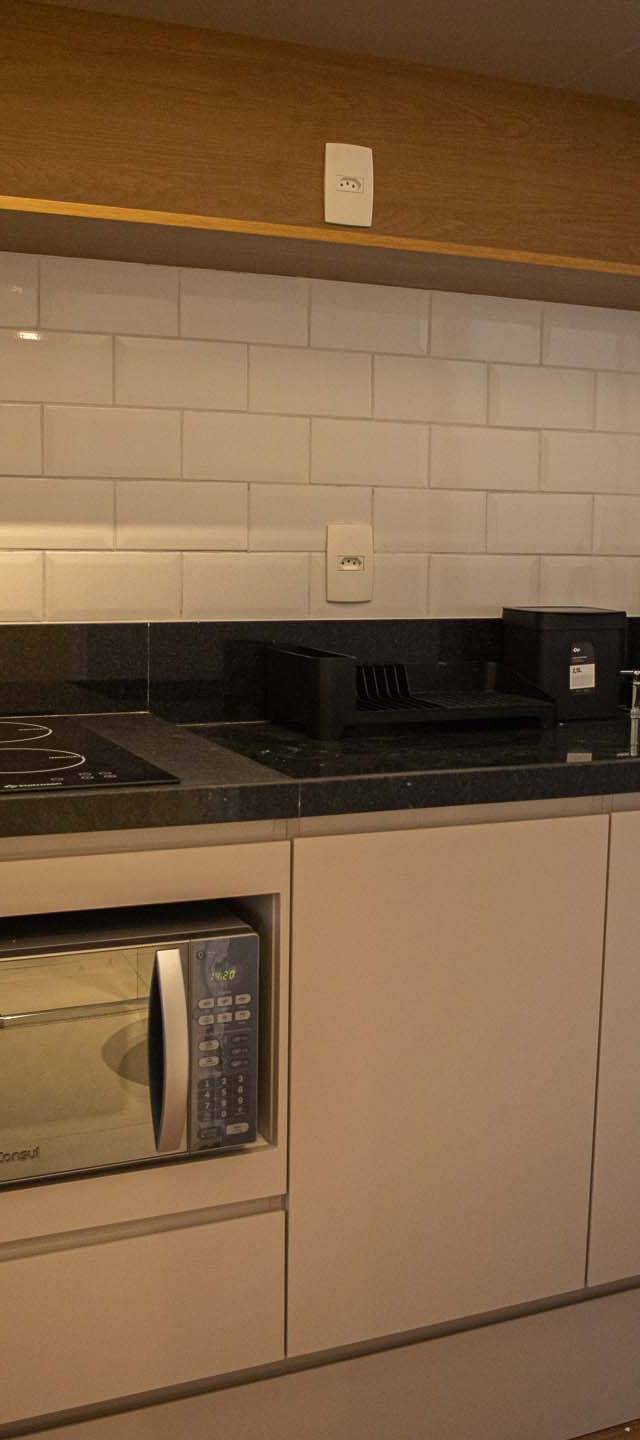 Obra pronta: Cozinha com armários claros, micro-ondas embutido, bancada de granito preto e metrô branco