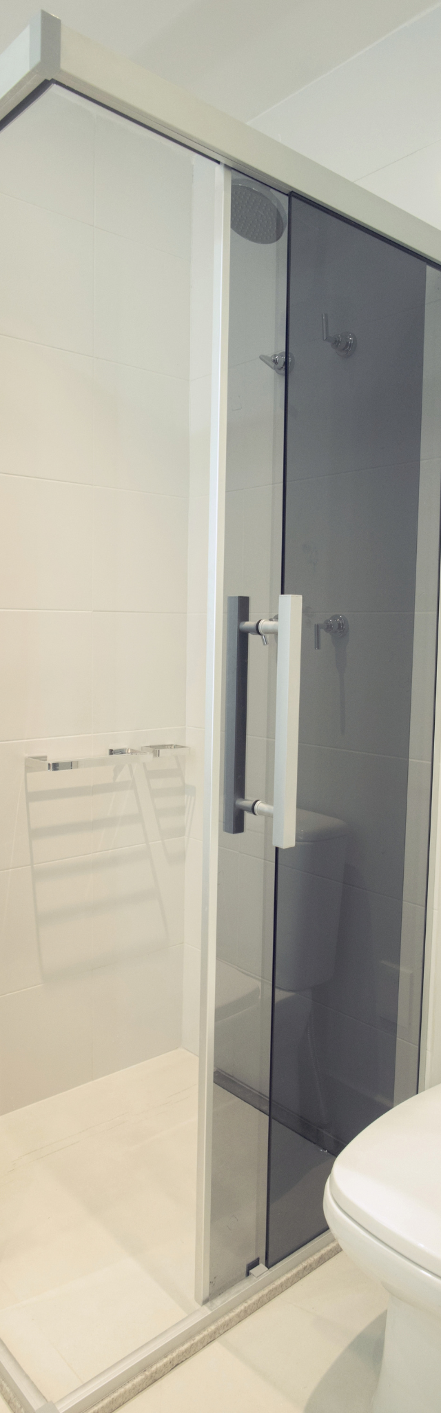 Obra pronta: Box de canto com vidro fumê ao lado do vaso sanitário, revestimento branco