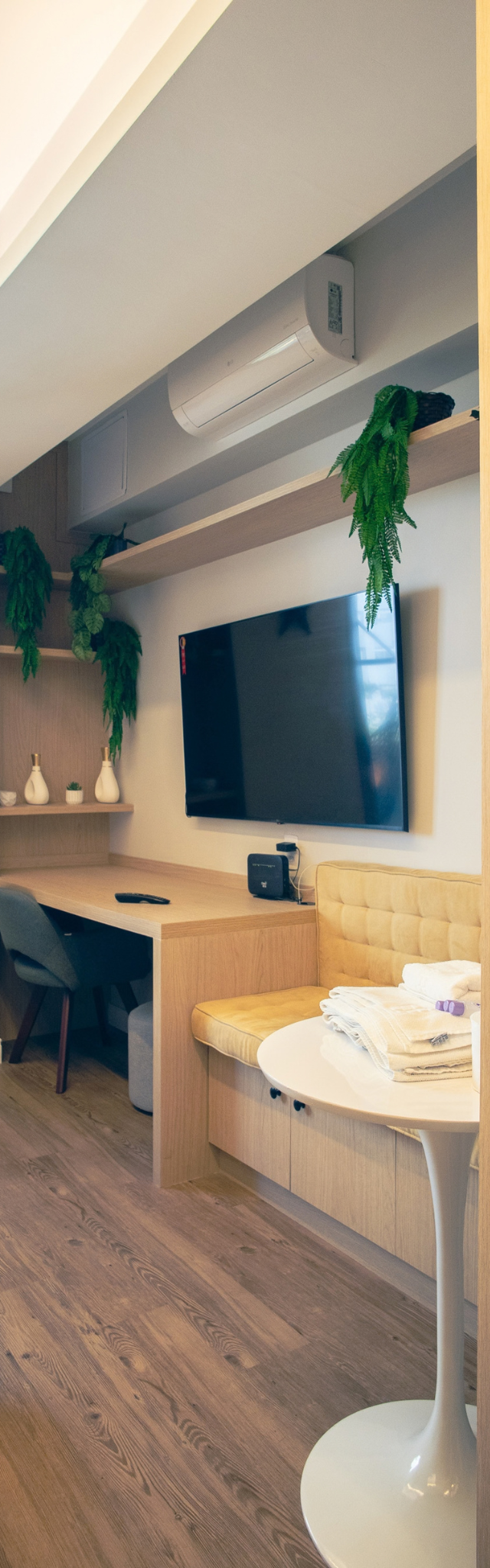 Obra pronta: Studio com mesa de trabalho, TV, banco estofado amarelo, mesa lateral branca e plantas
