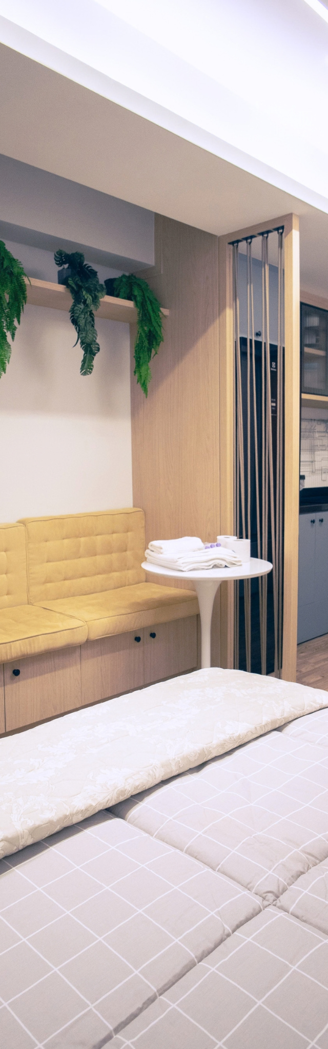 Obra pronta: Cama de casal com banco estofado amarelo, TV e cozinha ao fundo