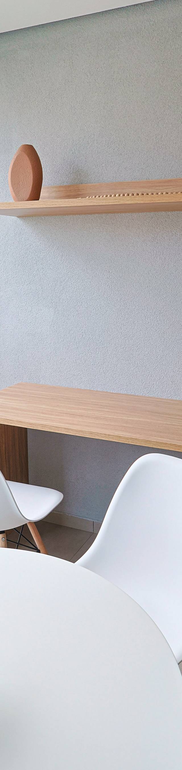 Obra pronta: Varanda com bancada de madeira, cadeiras brancas, prateleira com vasos e mesa redonda