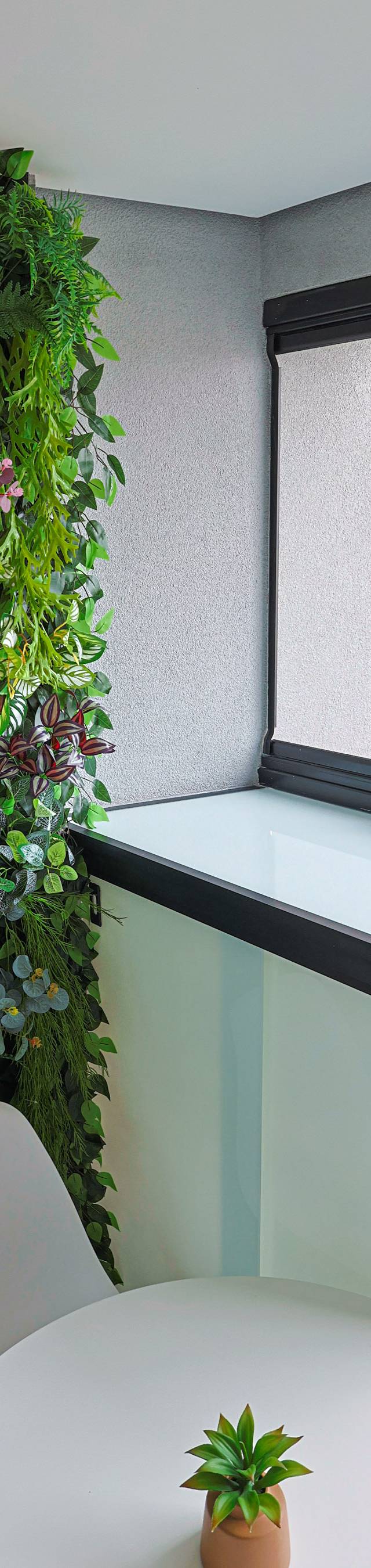 Obra pronta: Jardim vertical ao lado do armário de vidro da varanda, com mesa redonda branca