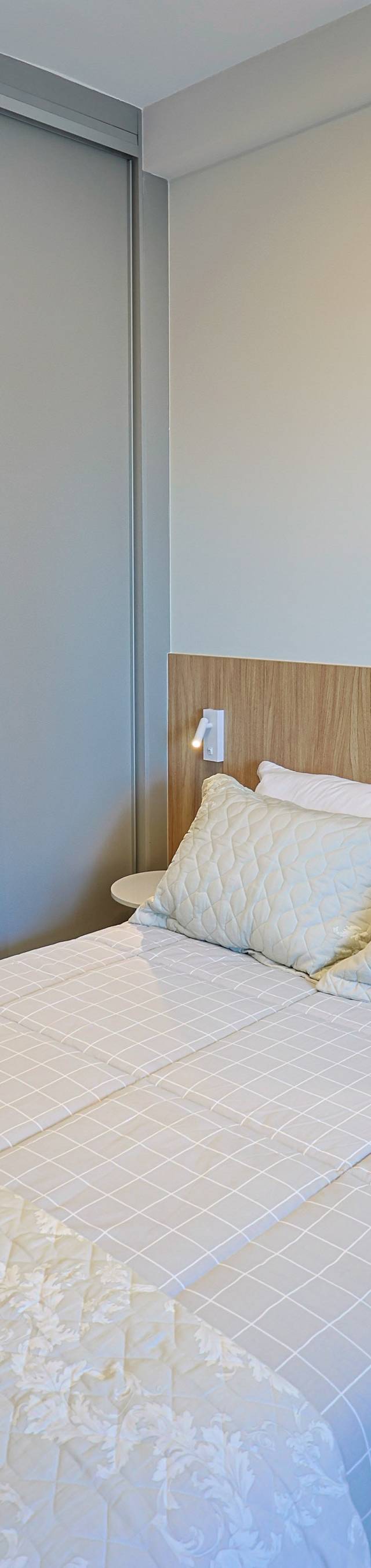 Obra pronta: Cama de casal com cabeceira de madeira e armário espelhado refletindo o quarto
