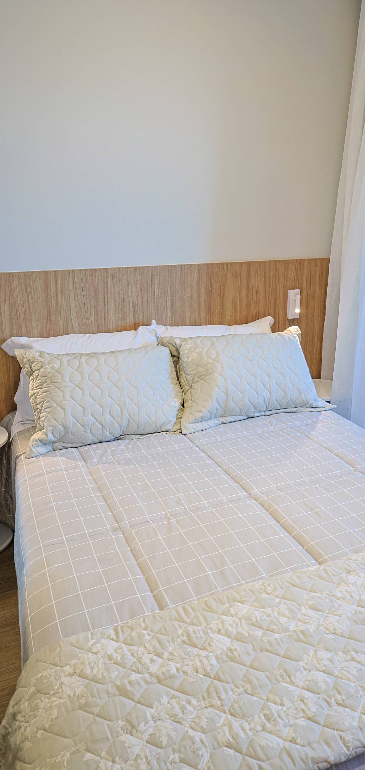 Obra pronta: Cama de casal com cabeceira de madeira, mesa lateral branca e cortina clara